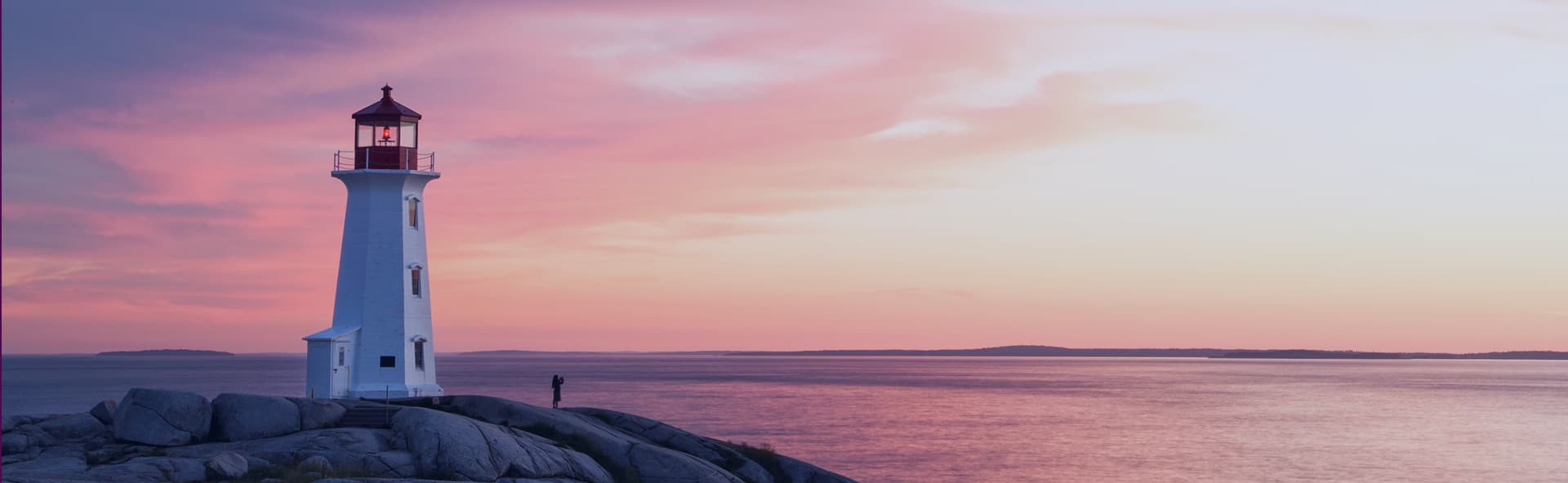 person on rock in distance with sunset
